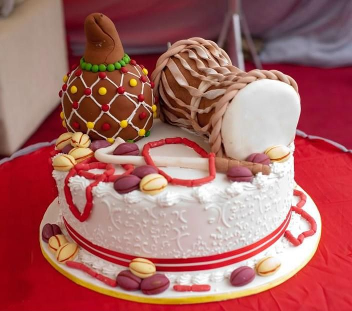 Wedding cake with accessories of traditional drum, cowries, and red beads