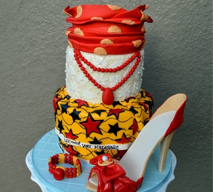 A three layered cake with ankara design with an edible shoe and bangle at the side.